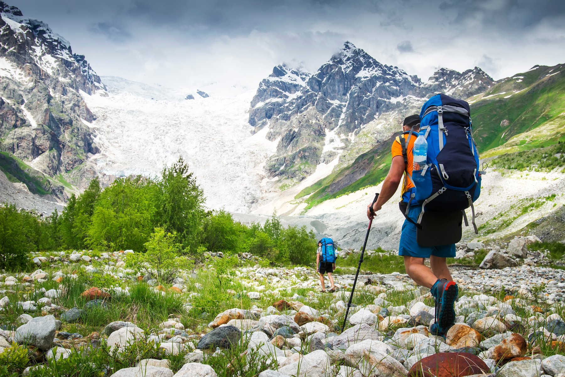 Climbers with hiking backpacks go to the mountain. hikers in mountains. Tourists hike on rocky mounts. Leisure activity on mountain trek in wild Svaneti region of Georgia. Groupe Hiking